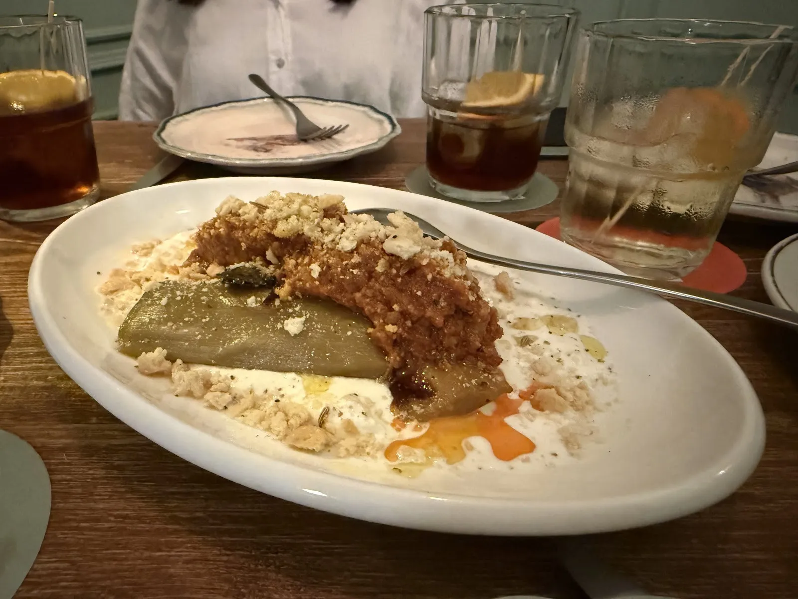 A dish with a crunchy topping, among glasses of vermouth